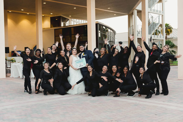 wedding couple posing with event staff