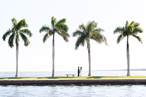 wedding couple on shore underneath palm trees